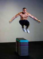 Black man doing box jumps in gym.